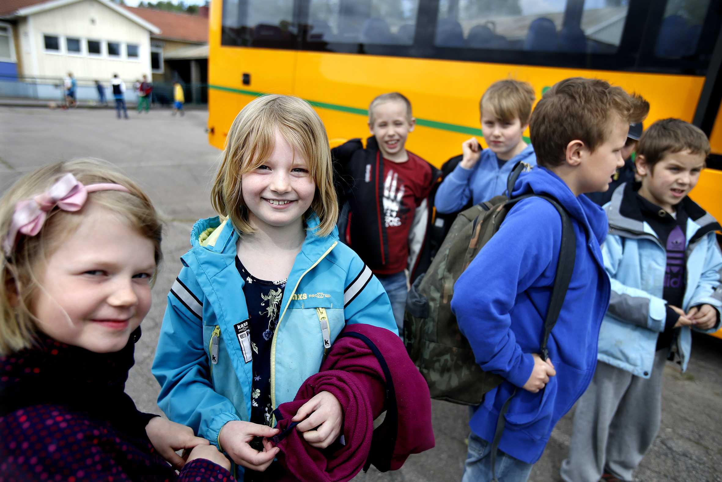 en skolklass som står utanför en skolbuss vid sin skola