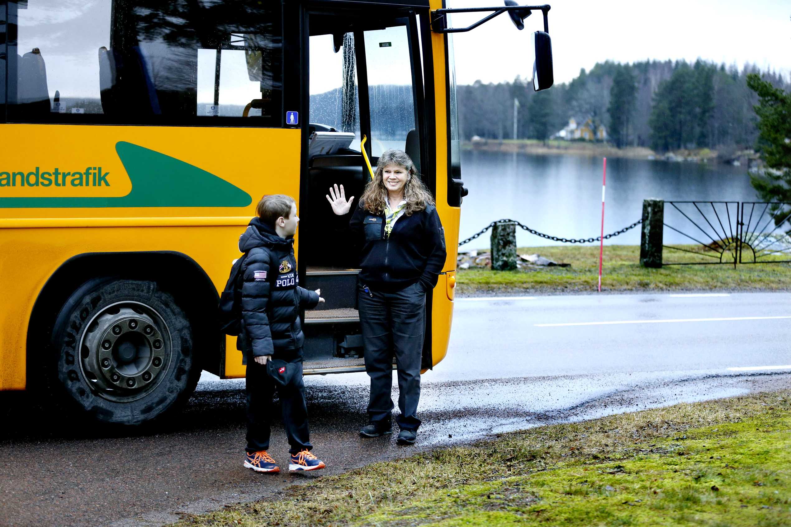 en chafför som glatt vinkar av en elev efter bussfärd